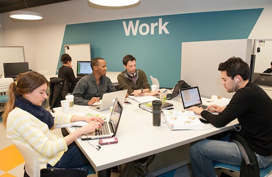 Students sit at a table at the C-Stop at UIC, a dedicated space for student studying and engagement.  These students are all seated with a laptop, typing on their laptops.