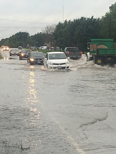 Cars and trucks drive through a flooded Illinois street.