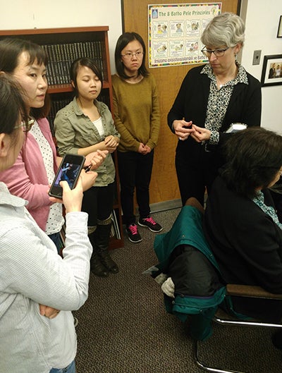 UIC professor Susan Buchanan stands with a group of Asian women, engaged in a question and answer session as part of the mercury research project.