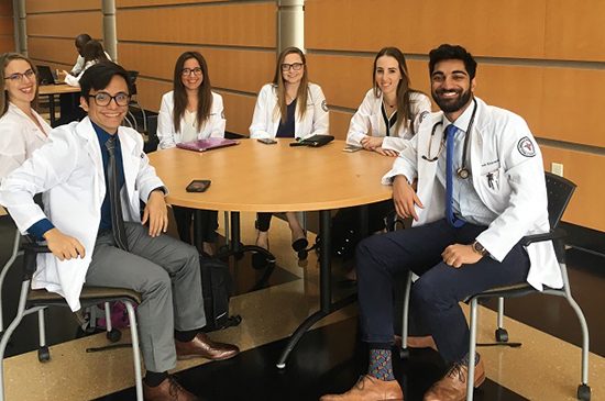 UIC medical students pose for a picture sitting at a round table.