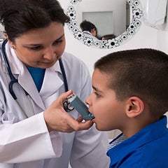 A doctor administers an inhaler to a young boy.