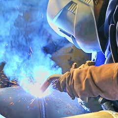 A welder works with a torch melting a piece of metal