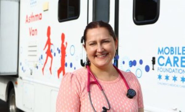 A UIC doctor poses for a picture standing in front of UIC's asthma van.