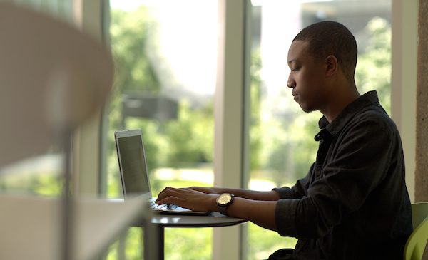 A student types on a laptop computer sitting in Douglas Hall on UIC's campus.
