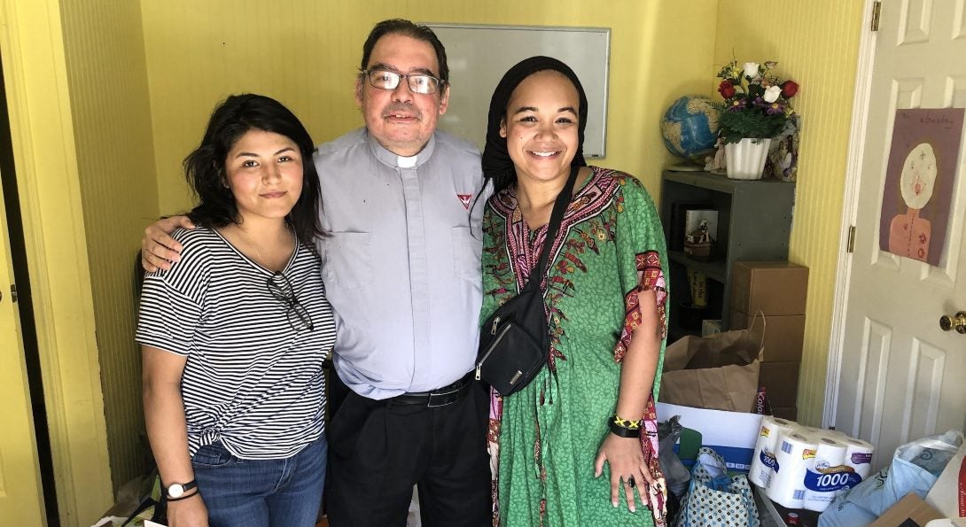 Students Kimberly Silva and Gabrielle Lodge pose for a picture with Father Roberto from St. Michael Church in Forest, Mississippi.