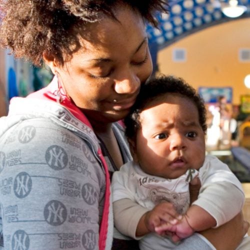 A mother holds her daughter while engaged in a playroom.