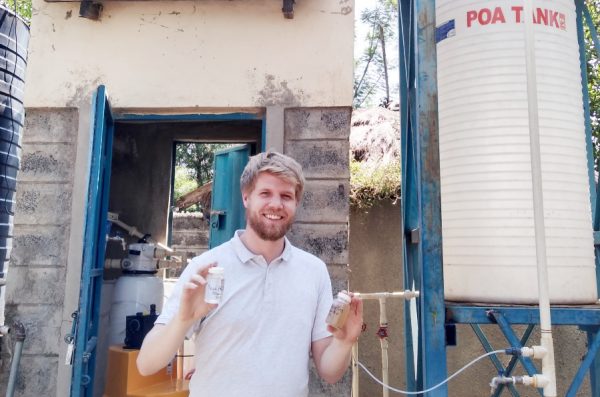 Student Colin Hendrickson holds up vials of water at a solar-powered water treatment location in Kenya.