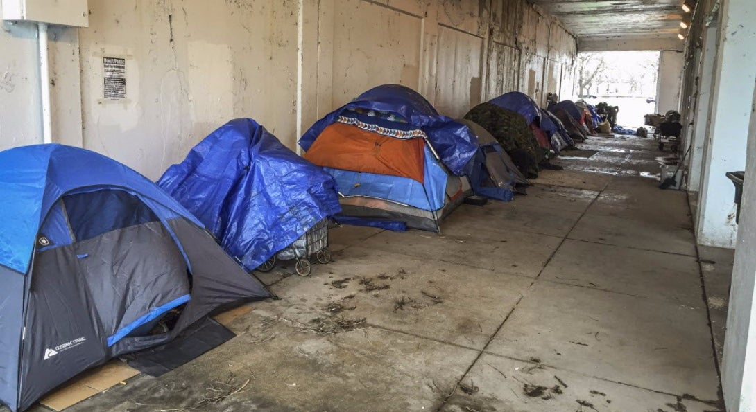 A group of tents lined up under an overpass in Chicago, presumably the temporary place of living for homeless residents of the city.