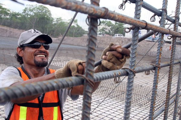 A construction worker adjusts a row of metal bars lining a construction site.