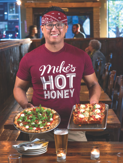 Derrick Tung poses for a photo holding two of his pizzas.