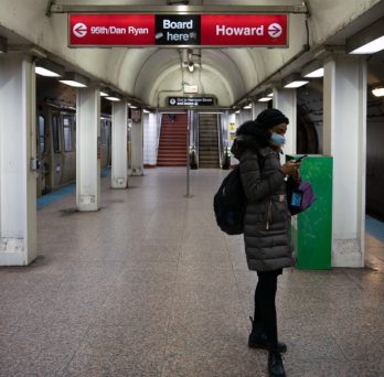 A solitary rider wears a mask while waiting for a CTA train at an underground station in Chicago.
                  