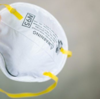 A person holds an N95 respirator mask in their hand.
                  