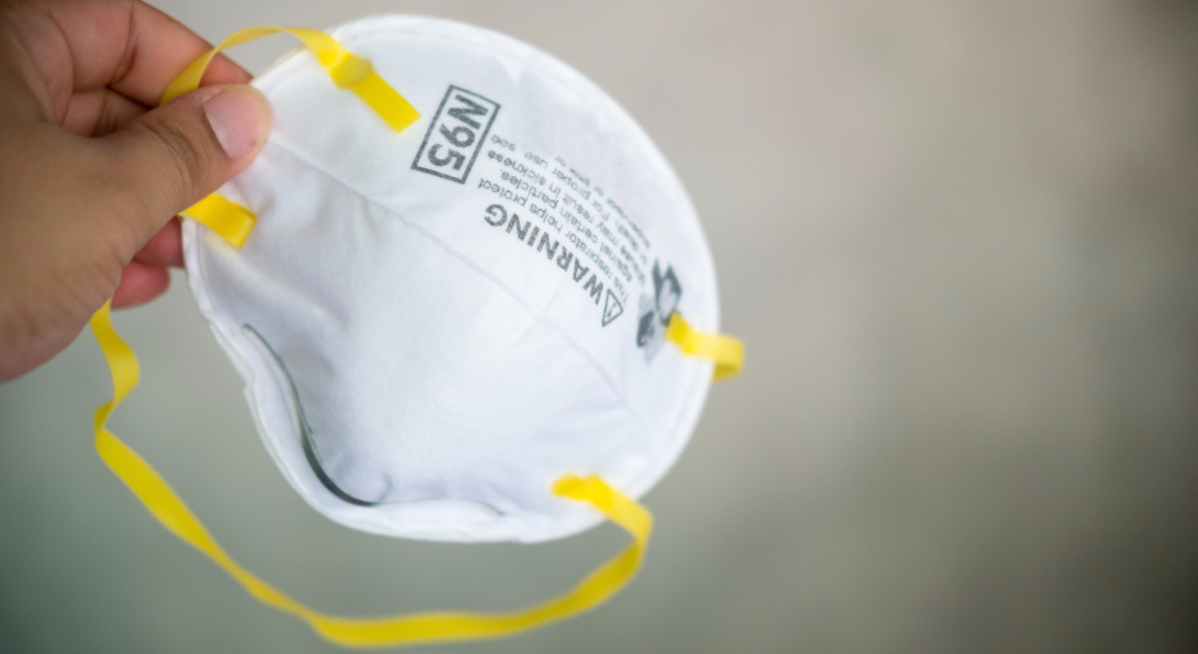 A person holds an N95 respirator mask in their hand.