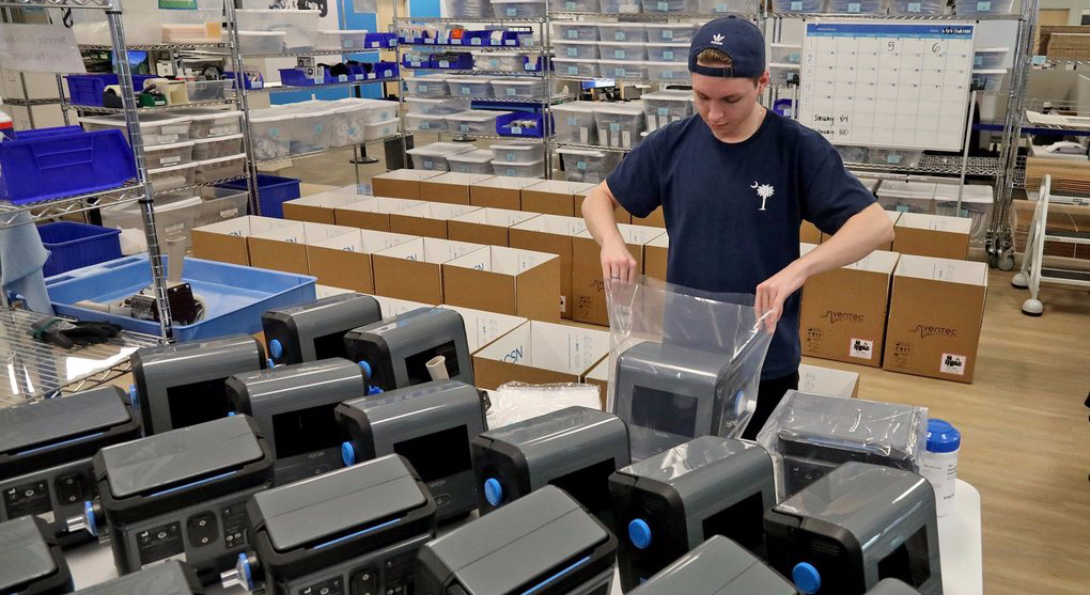 A worker packages a ventilator that has completed the manufacturing process.