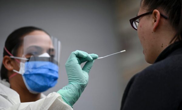 A medical professional prepares to perform a nasal swab COVID-19 test with a patient.