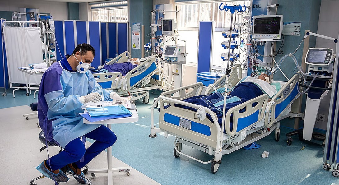 A doctor monitors the condition of two COVID-19 patients using ventilators.