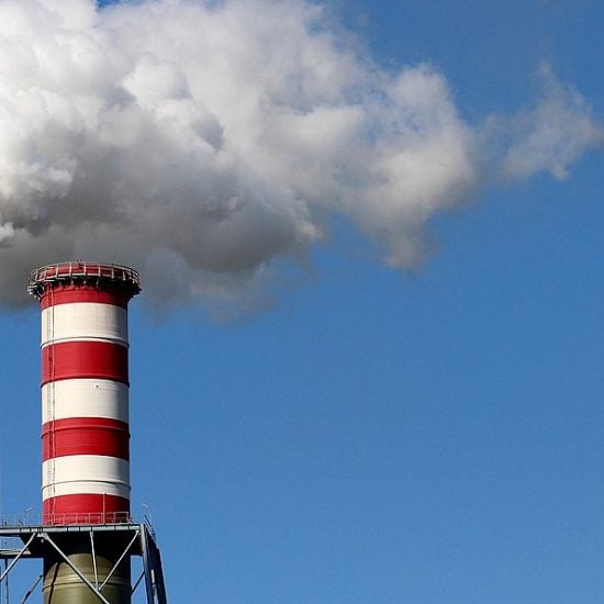 Two smokestacks emit a large cloud of white smoke.