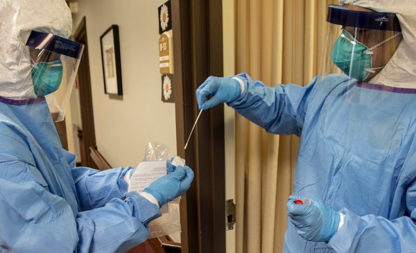 A medic with the Massachusetts National Guard takes a nasal swab that will be used to test for COVID-19 with a resident of a nursing home in Littleton, Mass.