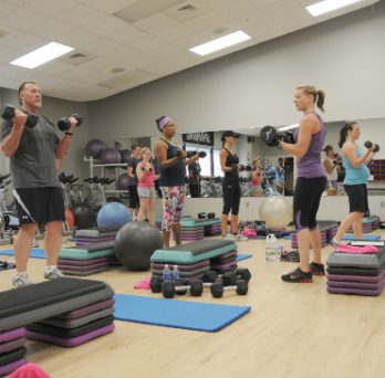 A workout class takes place in a gym. 