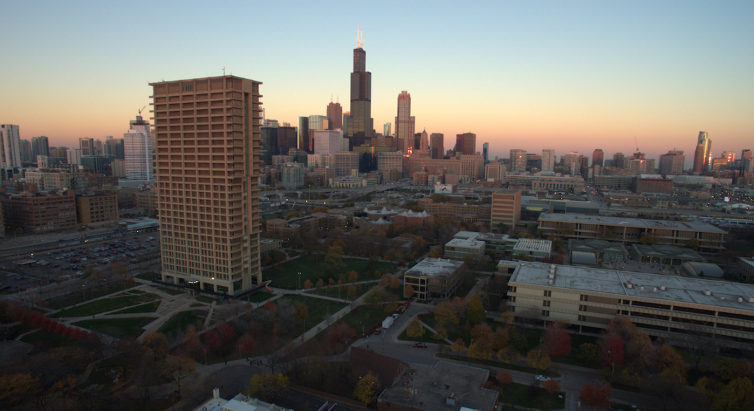 An aerial view of the Chicago skyline at dusk, with University Hall and UIC's East Campus in the foreground.