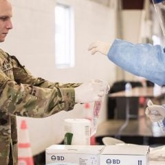 A COVID-19 test sample is processed by a member of the Illinois National Guard.