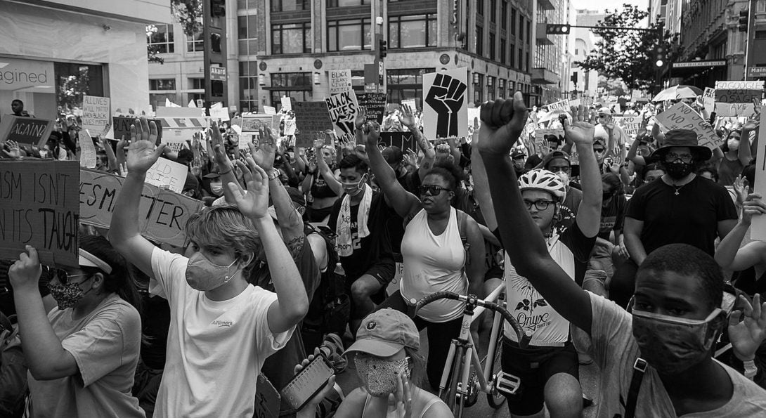 People in Dallas wear masks and hold up their hands in protest of the murder of George Floyd.