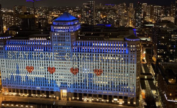 An aerial view of Merchandise Mart, lit up with a graphic of the Chicago flag and text stating 