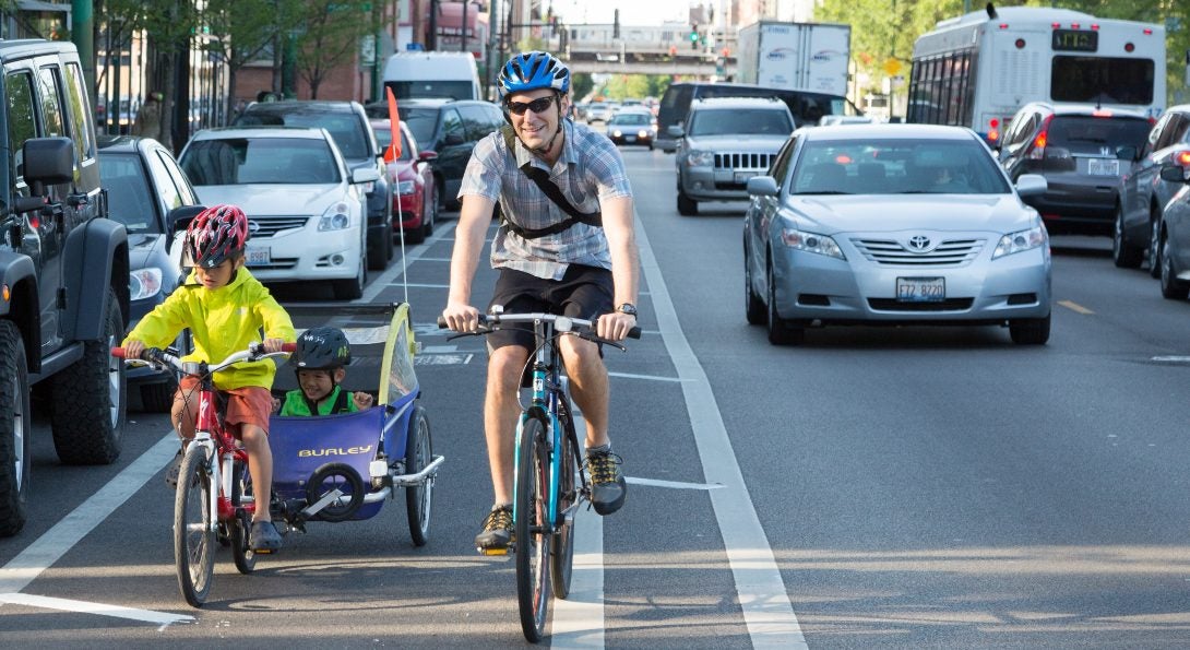 Two bicyclists travel down a buffered bike lane next to traffic in Chicago.