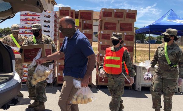 California National Guard members load potatoes into the back of a truck, with boxes of food stacked behind them.