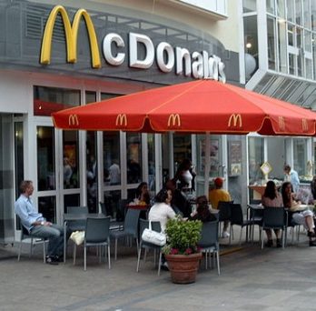The exterior of a McDonald's restaurant, with outdoor seating for dining. 
