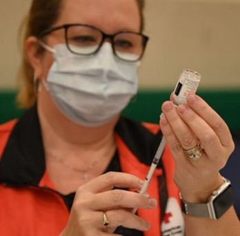 Angeline Mitchell, registered nurse and American Red Cross volunteer, prepares shots of the Moderna COVID-19 vaccine for the inoculations of critical medical staff and first responder volunteers onboard Naval Air Station Sigonella. 
