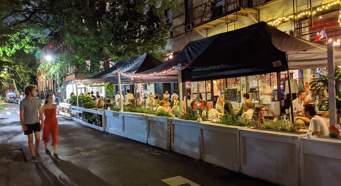 Patrons eat at outdoor tables under canopies during the COVID-19 pandemic.