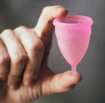 A person holds up a menstrual cup. 
