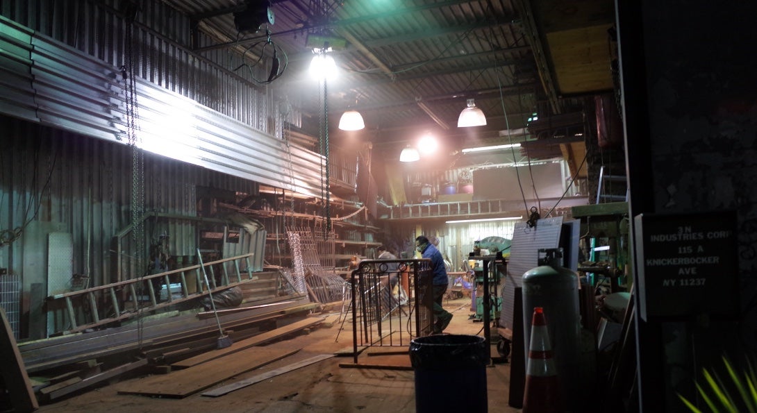 Workers walk among equipment laid across the floor of a warehouse.