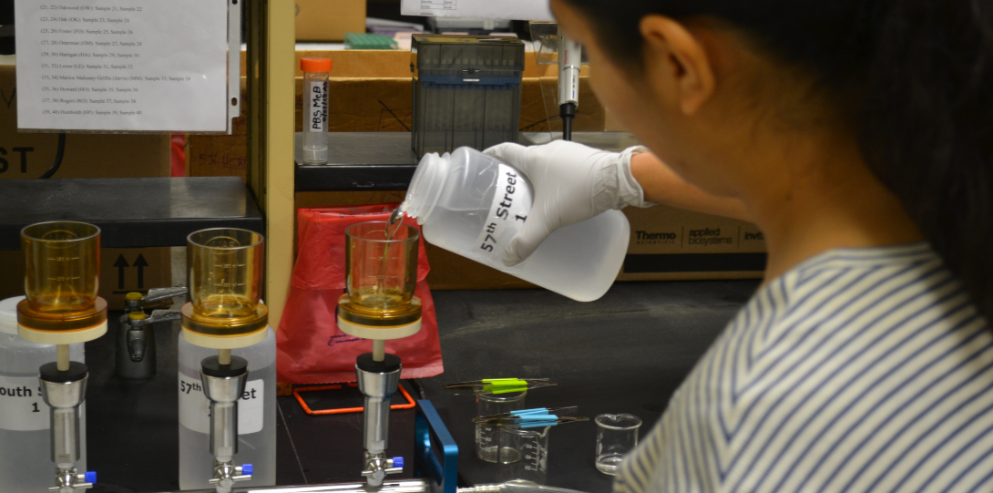 A lab technician pours water over filter paper.