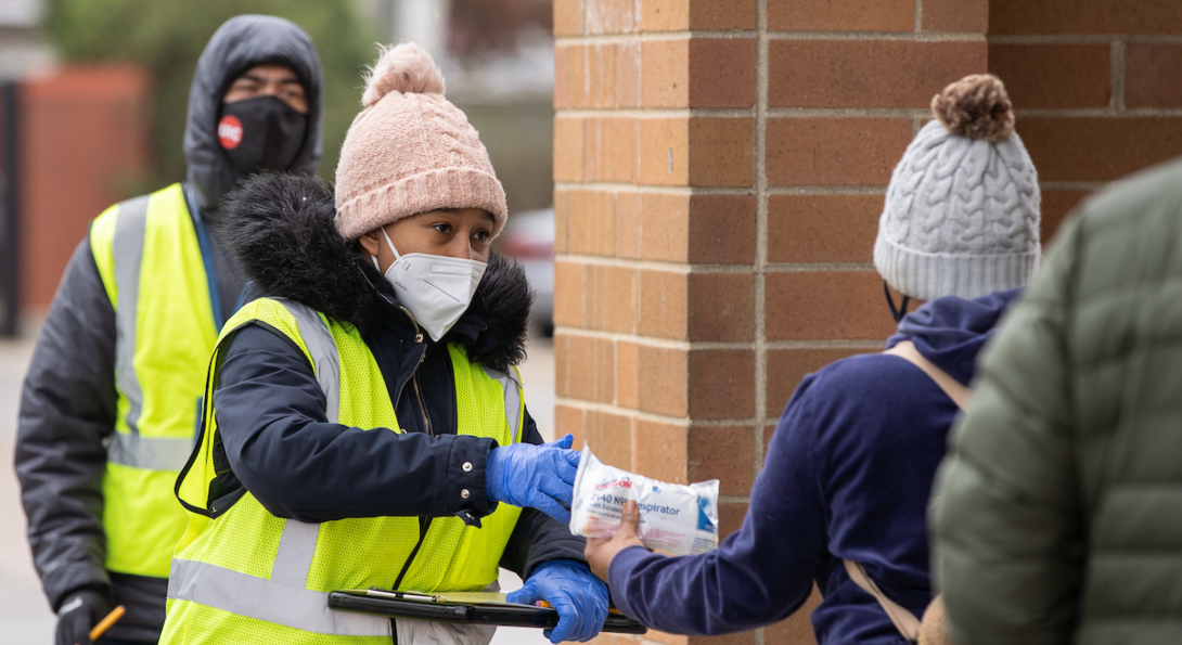 An outreach worker hands out masks to people at a Walgreens in the Mayfair neighborhood of Chicago.
