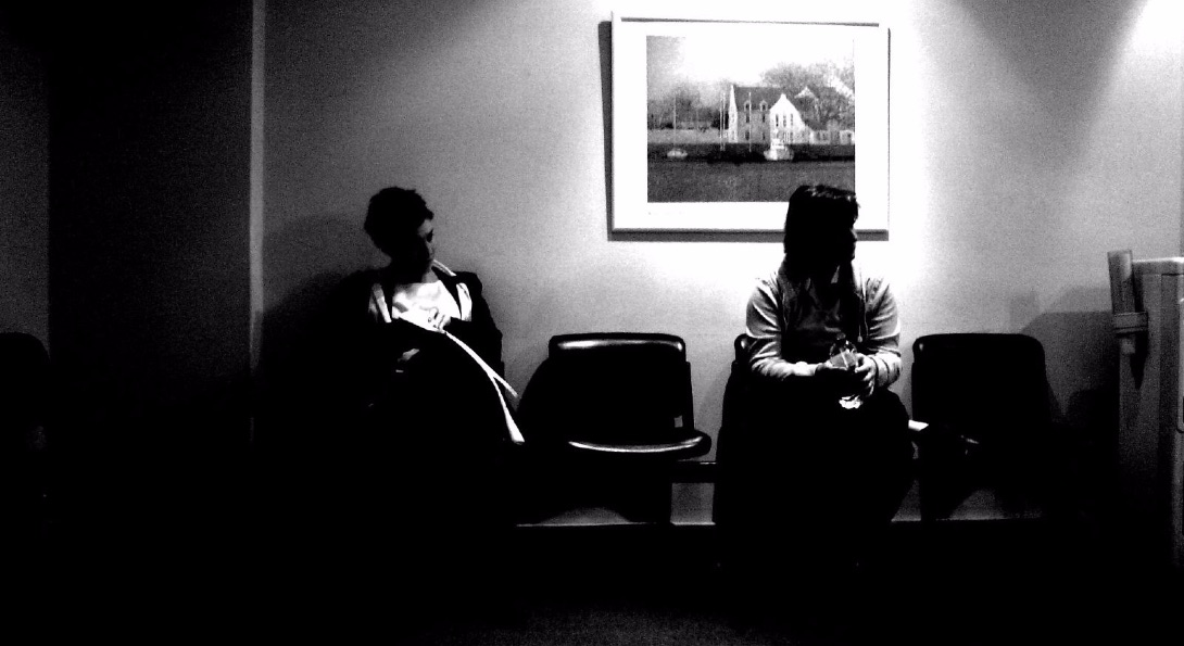 People sit in a doctor's office waiting room.