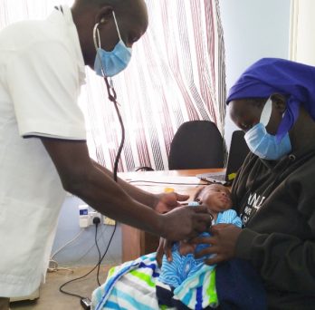 A doctor attends to the infant male son who is held in the arms of his mother, at a doctor's office in western Kenya.
                  