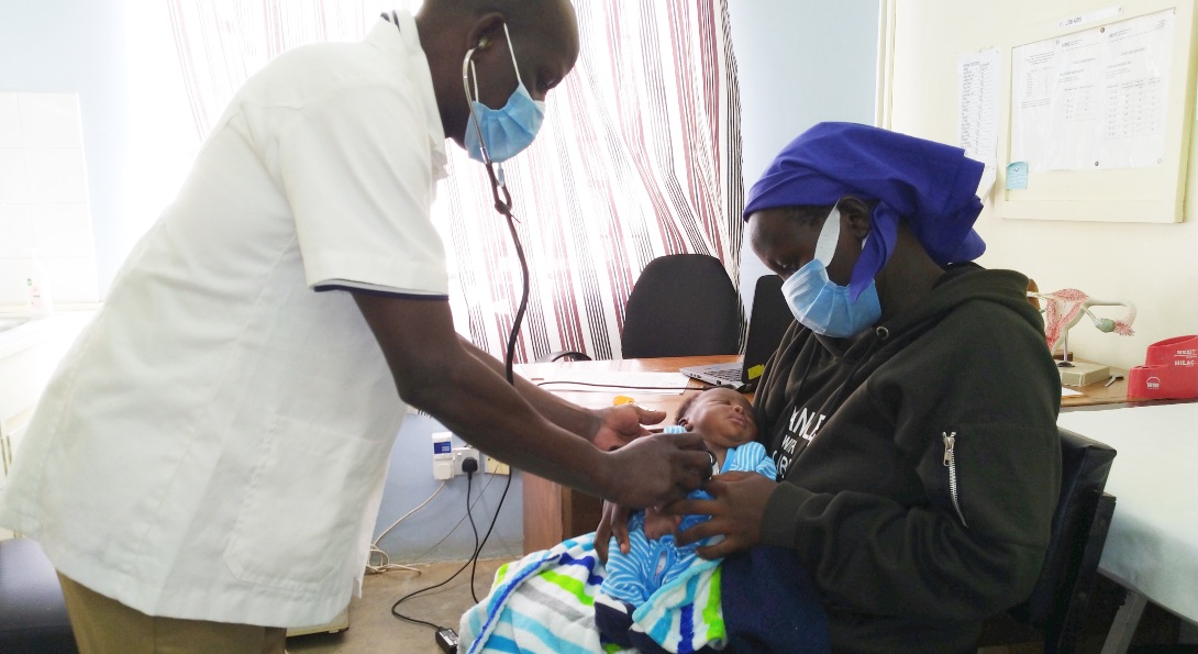 A doctor attends to the infant male son who is held in the arms of his mother, at a doctor's office in western Kenya.