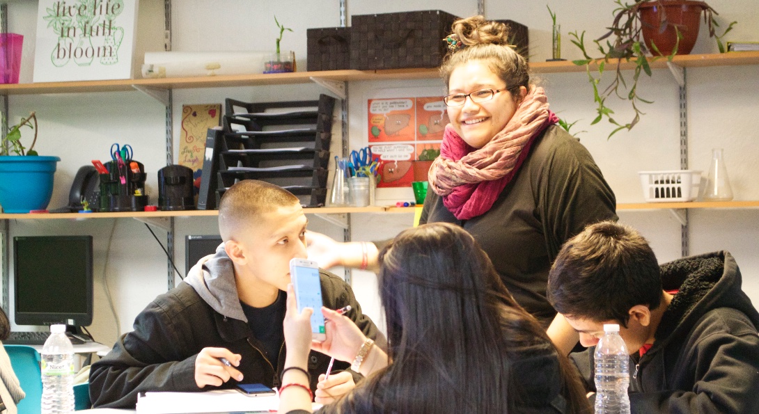 A teacher of Latina descent speaks to Latinx students in her classroom.