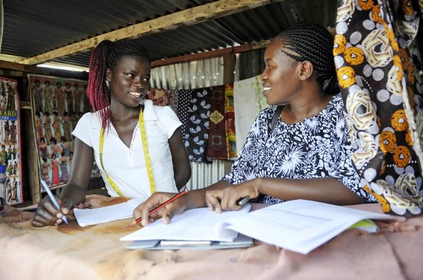 An adolescent girl in Kisumu completes a questionnaire with a researcher.