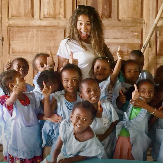 Hannah Bonecutter poses for a photo surrounded by a group of smiling children.