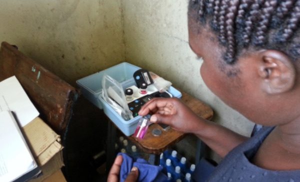 An SPH student in Kenya examines water purification samples in a vial.