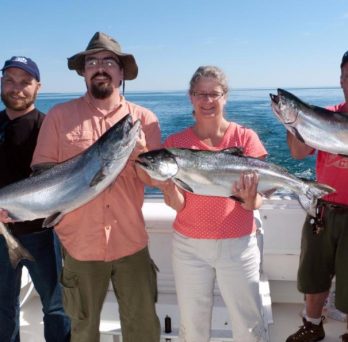 Charter boat customers hold up large fish they caught during their voyage.
                  