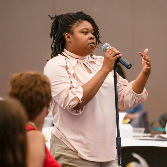 A person speaks from a microphone at the 2019 UIC Minority Health Conference.