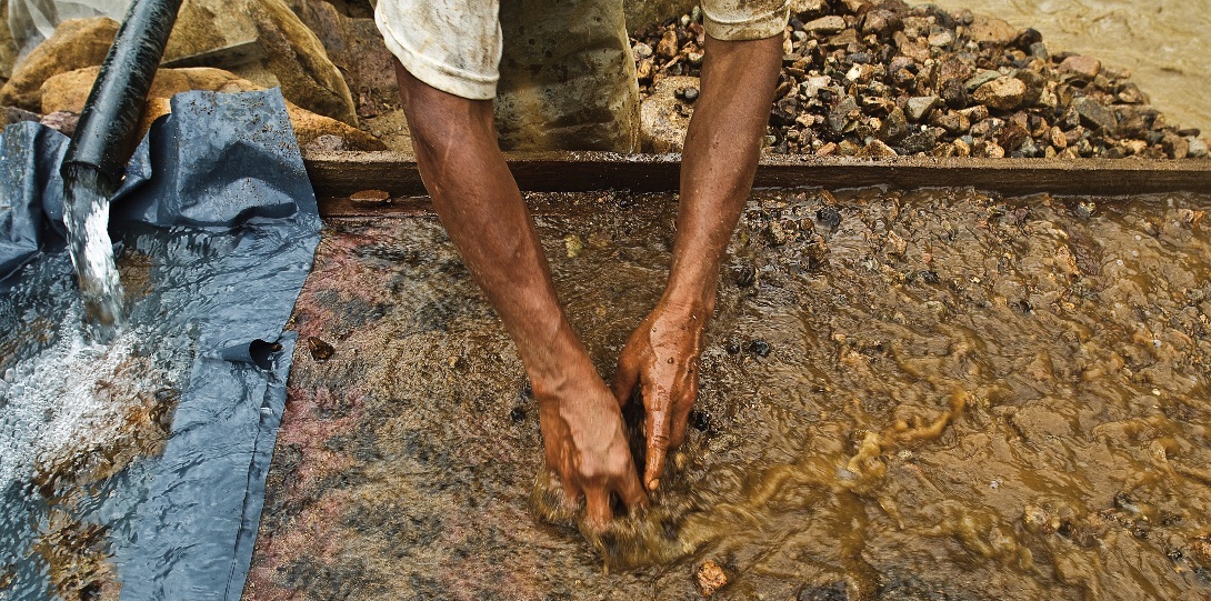 An artisanal gold miner sifts through silt combined with mercury as part of a gold mining process.