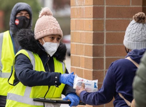A citizen public health worker hands out PPE to shoppers at a Chicago-area Walgreens.