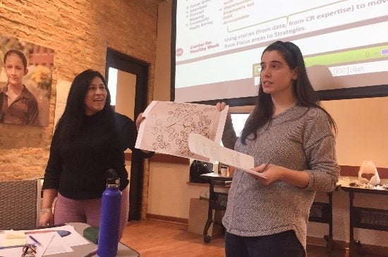 Two students share the results of a presentation at a community meeting.