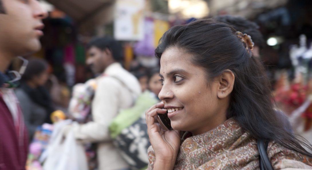 A woman in India talks on her phone while walking down a street.
