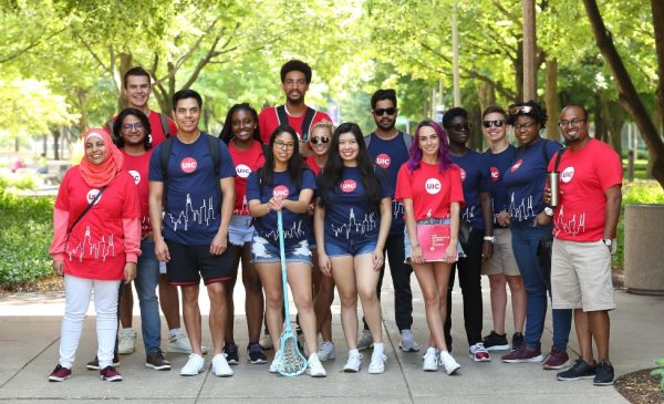 A diverse group of UIC students, all wearing UIC t-shirts, pose for a group photo on UIC's campus.